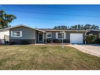 Gray house with white shutters, landscaped lawn, and a two-car garage at 29919 69Th N St, Clearwater, FL 33761