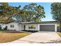 Charming single-story home with white brick, gray trim, well-maintained landscaping, and a gray two-car garage at 523 Deville E Dr, Largo, FL 33771