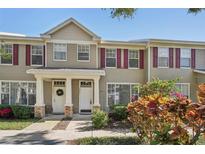 Tan two-story townhome with burgundy shutters and a small front yard at 13747 Forest Lake Dr, Largo, FL 33771