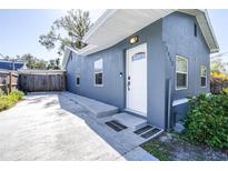 Newly renovated home with gray exterior, white door, and landscaped yard at 1512 W Kirby St, Tampa, FL 33604