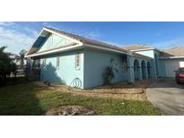 Light blue house with a landscaped yard, driveway, and partial view of the waterway at 2161 Aqui Esta Dr, Punta Gorda, FL 33950