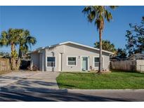 Newly renovated home with a light gray exterior, green door, and well-manicured lawn at 5516 Golden Dr, Tampa, FL 33634