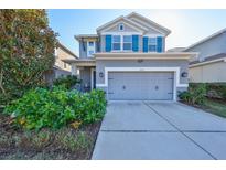 Gray two-story house with teal shutters, two-car garage, and landscaped front yard at 6337 Waves End Pl, Apollo Beach, FL 33572