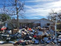 House exterior showing significant storm damage and debris in the front yard at 7930 Causeway S Blvd, St Petersburg, FL 33707