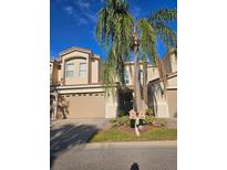 Tan three-story townhouse with two-car garage, and palm trees at 10405 Saint Tropez Pl # 10405, Tampa, FL 33615