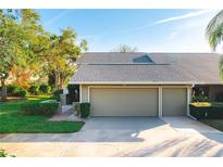 Tan two-car garage villa with gray roof, landscaping, and paved driveway at 3401 Avenida Madera # B, Bradenton, FL 34210