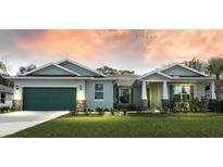 Two-story house with green garage door, stone accents, and landscaped lawn at 142 Fairway Rd, Rotonda West, FL 33947