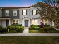 Two-story townhome with gray siding, landscaping, and a welcoming front entrance at 14470 Promenade Pkwy, Odessa, FL 33556