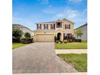 Two-story house with a brick driveway and landscaping at 1192 Multiflora Loop, Lutz, FL 33558