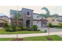 Two-story home with stone accents and palm trees at 12779 Fisherville Way, Riverview, FL 33579