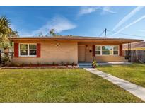 Tan brick ranch home with red shutters, landscaped lawn, and walkway at 2621 13Th N St, St Petersburg, FL 33704