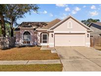 One-story house with pink stucco exterior, two-car garage, and fenced yard at 1202 Sawdust Ct, Valrico, FL 33596