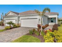 Charming home featuring a well-manicured lawn, a brick driveway, and a two-car garage at 18475 Green Garden Ct, Venice, FL 34293