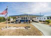 Florida mobile home with carport, landscaped yard, and American flag at 5312 Mary St, Zephyrhills, FL 33542