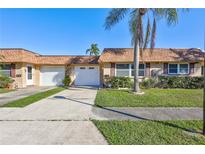 Tan two-unit building with white garage doors, and a palm tree at 1006 Cara Dr # 1006, Largo, FL 33771