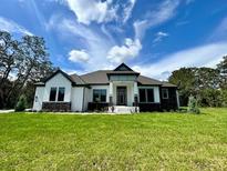 Beautiful single-story home with a manicured lawn and a modern, eye-catching exterior design at 13400 Haflinger Way, Hudson, FL 34667