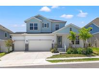 Two-story house with light blue siding, white garage, and landscaping at 1532 Gopher Loop, Tarpon Springs, FL 34689