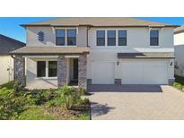 Charming home featuring stone accents, a paved driveway, and a three-car garage at 21291 Snowy Orchid Ter, Land O Lakes, FL 34637
