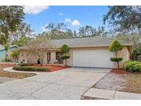 Tan house with white garage door, landscaping, and curved driveway at 2761 Westchester N Dr, Clearwater, FL 33761