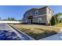 Two-story townhome with gray siding, landscaping, and a paved driveway at 31225 Claridge Pl, Wesley Chapel, FL 33543