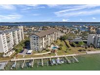 Beautiful aerial view of a waterfront condo community with docks, a pool, and lush landscaping near the bay at 650 Island Way # 106, Clearwater Beach, FL 33767