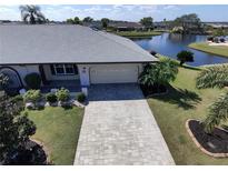 Inviting front of home with manicured lawn, stone paver driveway, and view of the adjacent pond at 1506 Bentwood Dr, Sun City Center, FL 33573