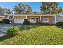 Ranch-style home with stone accents, covered porch, and well-manicured lawn at 6474 Pine Meadows Dr, Spring Hill, FL 34606