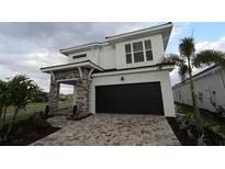 Two story home with a paver driveway, black garage door, and stone pillars at the front entry at 664 Allora Ave, Nokomis, FL 34275