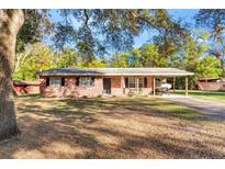 Brick ranch home with covered carport, spacious yard, and mature trees at 7846 Forbes Rd, Zephyrhills, FL 33540