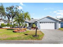 Well-maintained house with a landscaped lawn, two palm trees, and a two-car garage at 8747 Glen Lakes N Blvd, St Petersburg, FL 33702