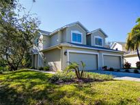 Tan two-story house with three-car garage, manicured lawn, and palm trees at 472 Harbor Ridge Dr, Palm Harbor, FL 34683