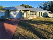 Charming single story home with a metal roof, attached garage, and well-manicured lawn at 1116 Carmona Ave, Spring Hill, FL 34608