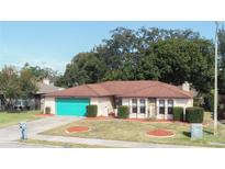 Cute ranch home with teal garage door, mature landscaping, and a spacious yard at 12609 Shadow Ridge Blvd, Hudson, FL 34669