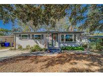 Charming single story home with gray exterior, landscaping, and large oak tree at 1638 St Catherine W Dr, Dunedin, FL 34698
