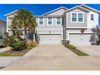 Two-story townhome with attached two-car garage and landscaped front yard at 5805 Grand Sonata Ave, Lutz, FL 33558