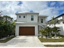 Modern two-story home with a sleek design, large windows, and a nicely landscaped front yard and driveway at 817 Bay Point Dr, Madeira Beach, FL 33708