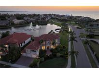 Stunning waterfront home with lush landscaping, fountain, and a beautiful tile roof at sunset at 1414 Alhambra Dr, Apollo Beach, FL 33572