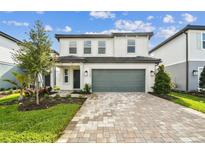 Charming two-story home featuring a paved driveway, attached two-car garage, and well-manicured landscaping at 10328 Cross River Trl, Parrish, FL 34219