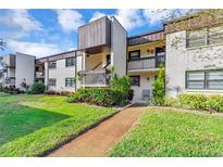 Condo building exterior with walkway and landscaping in daytime at 2400 Winding Creek Blvd # 24-203, Clearwater, FL 33761