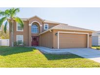 Two-story house with a red door, attached garage, and well-manicured lawn at 25028 Hyde Park Blvd, Land O Lakes, FL 34639