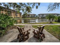 Scenic community view featuring a serene lake, lush landscaping, and relaxing Adirondack chairs, perfect for enjoying the outdoors at 5817 Park N St # 204, St Petersburg, FL 33709