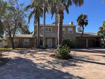 Two-story home with paver driveway, surrounded by palm trees at 4010 Belle Vista Dr, St Pete Beach, FL 33706