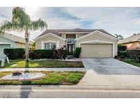 Charming single-story home featuring a manicured lawn, mature landscaping, and a two-car garage at 5627 War Admiral Dr, Wesley Chapel, FL 33544