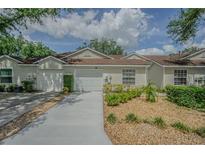 Charming townhome with neutral siding, a well-manicured lawn and a private one-car garage at 21550 Clubside Loop, Lutz, FL 33549
