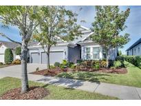 Single-story home with gray exterior, three-car garage, and well-manicured landscaping at 7506 Parkshore Dr, Apollo Beach, FL 33572