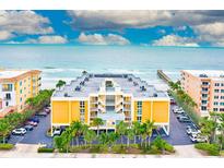 Aerial view of beachfront condo building with ocean and pier views, parking, and lush landscaping at 16308 Gulf Blvd # 303, Redington Beach, FL 33708