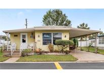 Bright yellow single wide mobile home with covered porch and landscaped yard at 27466 Us Highway 19 N # 103, Clearwater, FL 33761