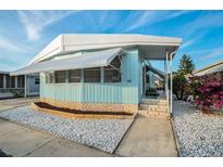 Light blue manufactured home with white awning, landscaping, and a paved driveway at 3301 Alt 19 # 252, Palm Harbor, FL 34683