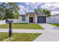 Charming home featuring a gray garage door, red front door and well-maintained green lawn at 8317 N Ogontz Ave, Tampa, FL 33604