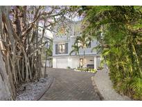 Charming two-story home with a brick driveway, lush landscaping, and mature trees at 122 White Ave, Anna Maria, FL 34216